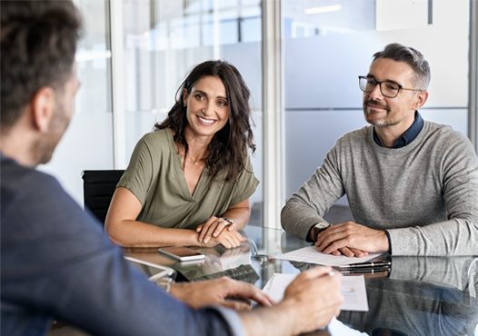 Stock photo, man and woman couple sitting at conference room table meeting with an advisor