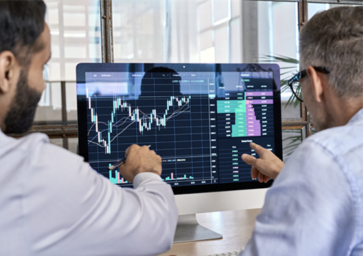 Stock photo, two men in suits pointing to computer screen showing financial market price chart